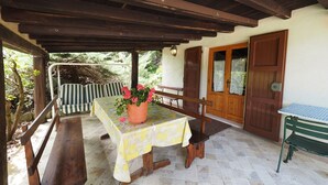 An outdoor patio with a table and benches, a potted plant, and a wooden door. - Glicine, romantic cottage with outdoor patio, on the hills of San Gimignano (San Gimignano)