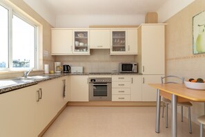A kitchen with a microwave, oven, and cabinets. There is a window providing natural light and a view of the outside.