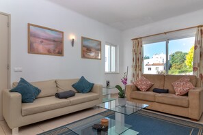 Ein Wohnzimmer mit zwei beigen Sofas, einem Glastisch und zwei Bildern an der Wand.