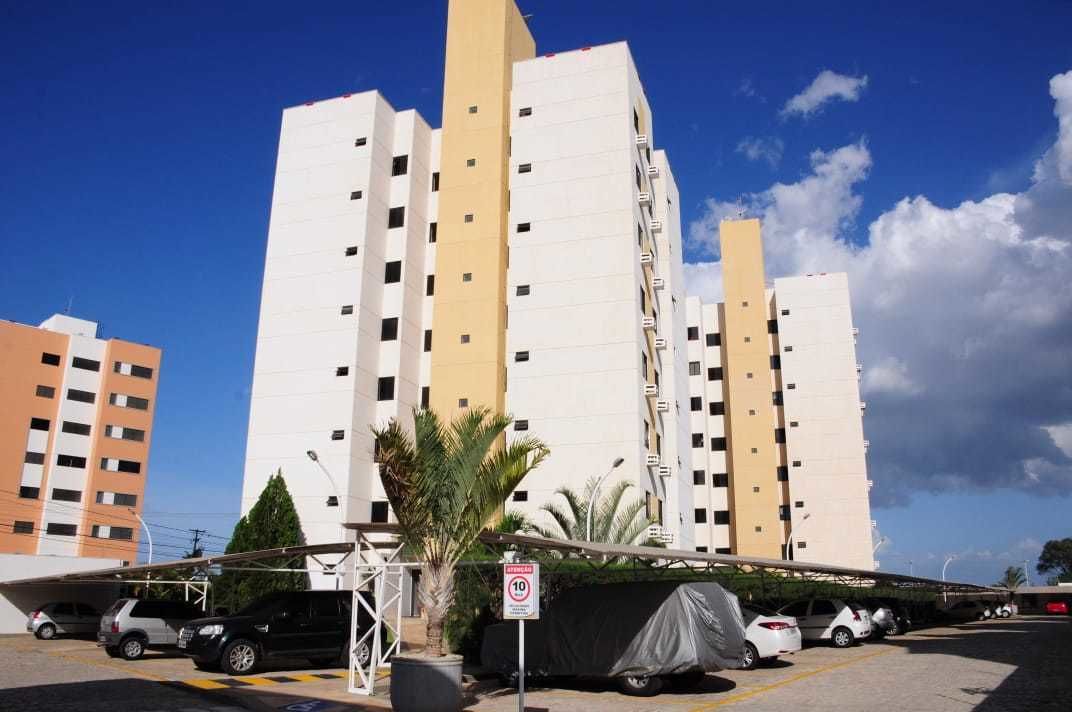 Edifício residencial com vários andares e área de estacionamento na frente.