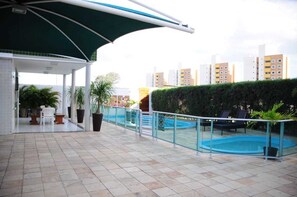 A rooftop pool area with a glass railing, lounge chairs, and potted plants. - Omar do Rio - M602 (Mossoro)
