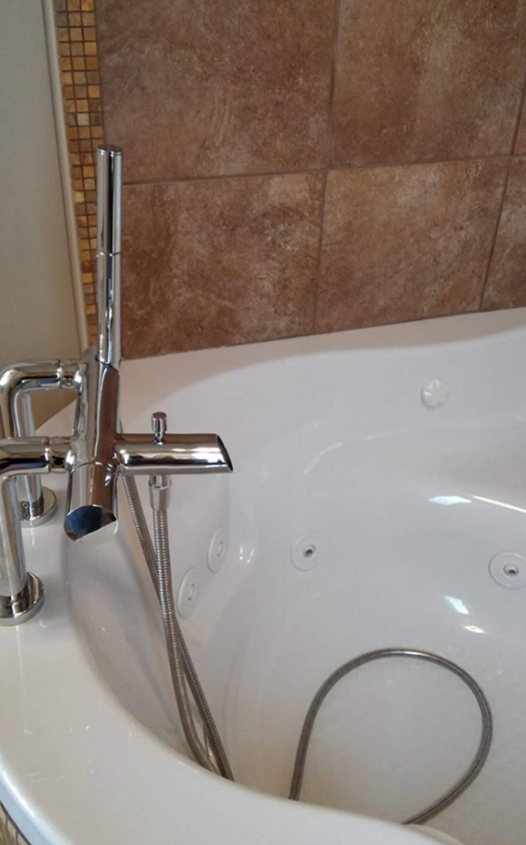 Una bañera con ducha de mano y grifo integrado.