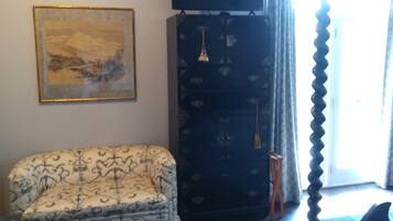 A room with a bed, a chair, a TV, a painting, and a wardrobe.