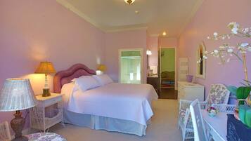 A bedroom with a bed, bedside tables, a chair, a table, and a mirror.