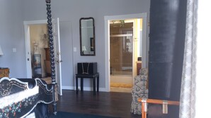 A bedroom with a four-poster bed, a mirror, a small table, and a chair. - Inntiquity A Country Inn (Logansport)