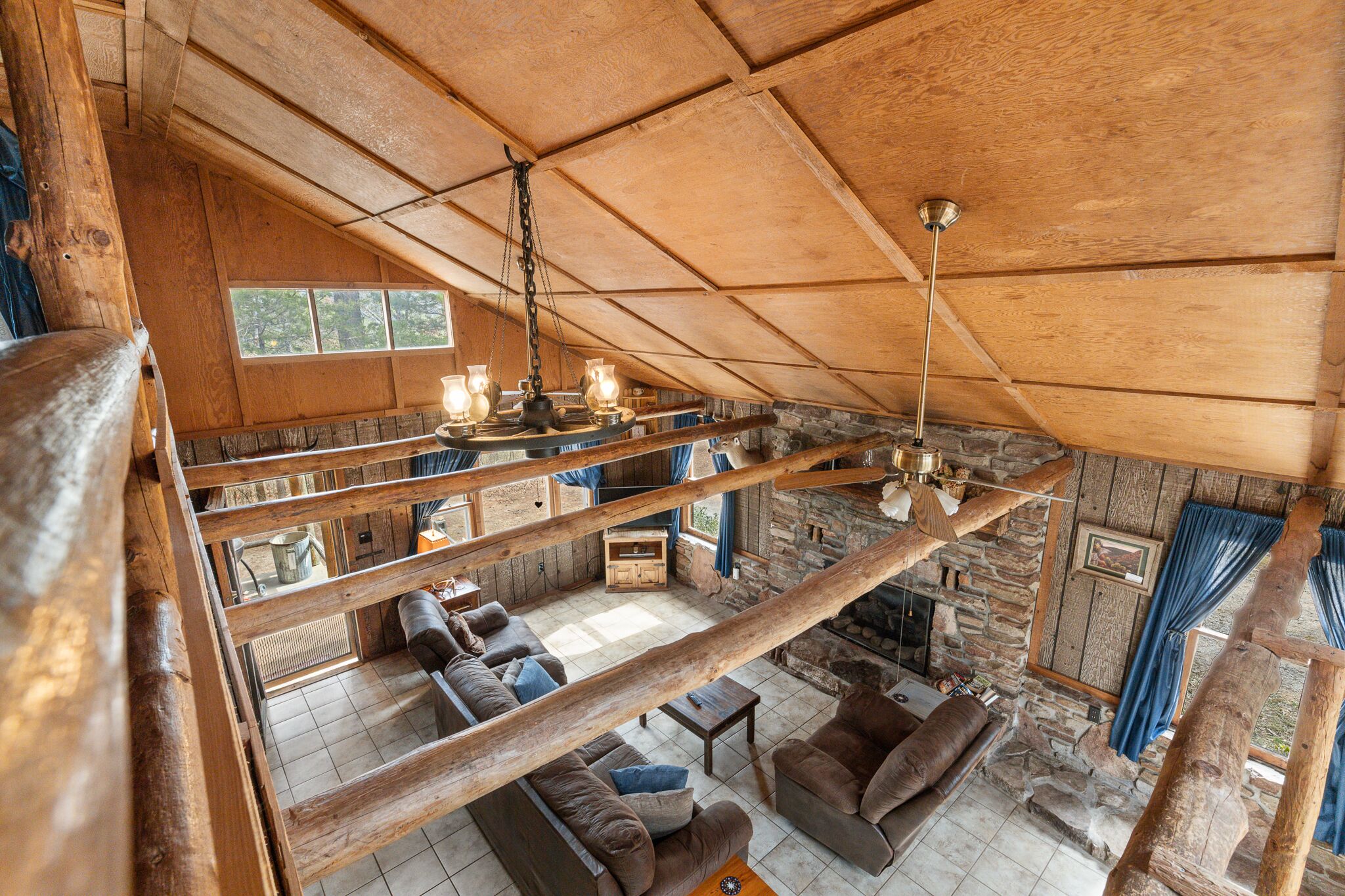 Een rustiek houten interieur met een zitgedeelte op een entresol, stenen muren en een open haard.