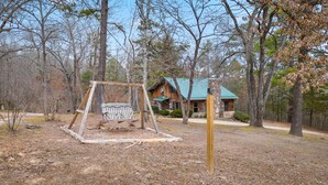 A rustic cabin with a swing set in a wooded area. - Rustic, close to buffalo river, secluded getaway, king bed, hiking ,WIFI (Jasper)