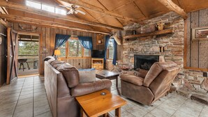 A rustic cabin interior with a stone fireplace, leather sofas, and a wooden ceiling. - Rustic, close to buffalo river, secluded getaway, king bed, hiking ,WIFI (Jasper)