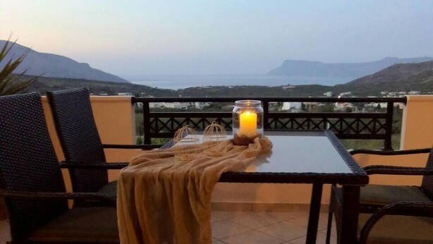 Una terraza con mesa y sillas, una vela y vistas a las montañas.