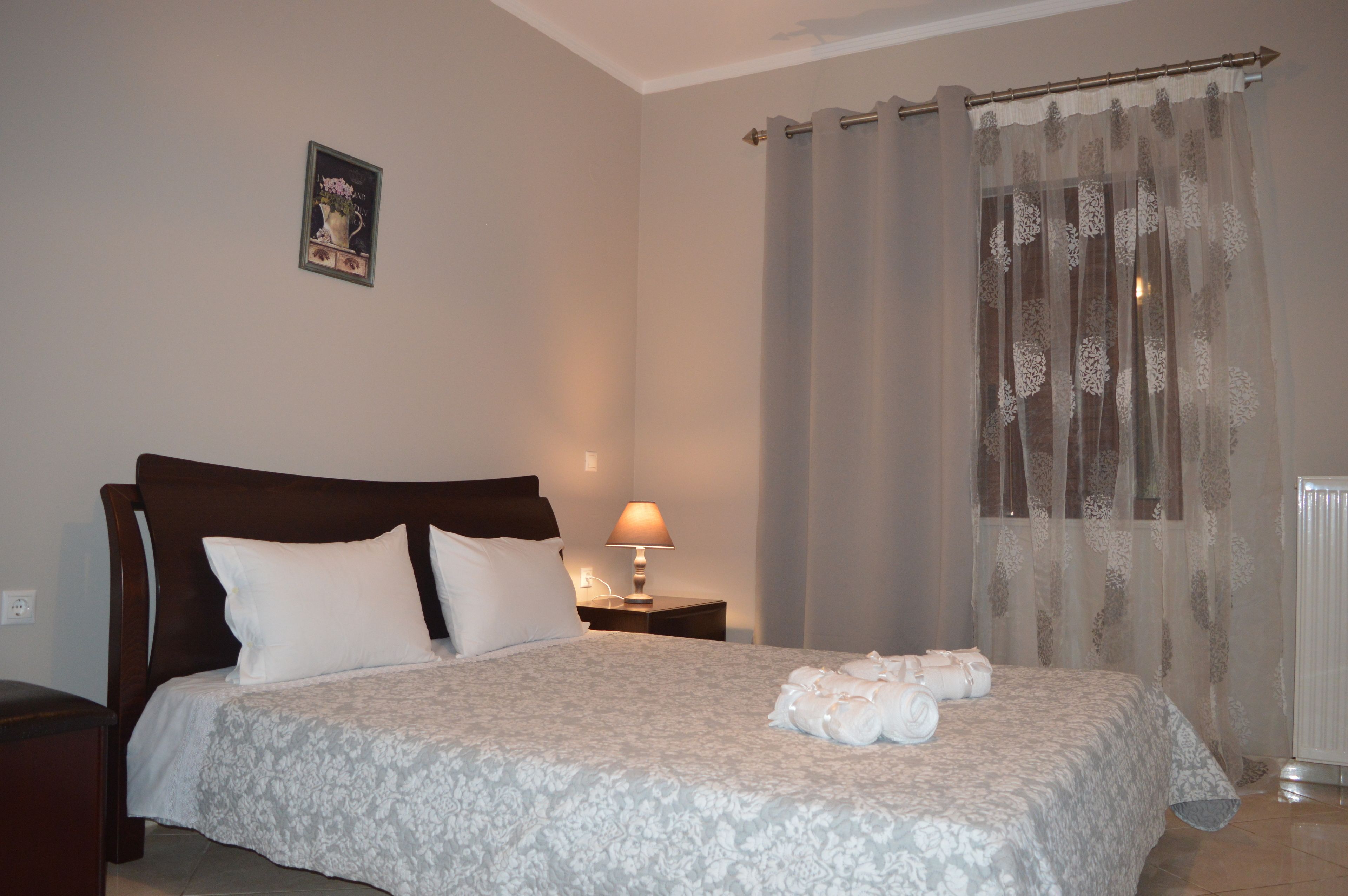 A neatly made bed with a floral bedspread, a bedside lamp, and a framed picture on the wall.