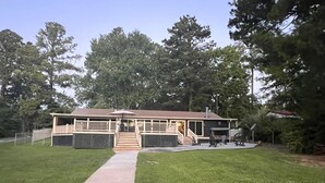 A two-story house with a deck, a covered patio, and a fenced yard. - Waterfront Retreat in Toledo Bend (Many)