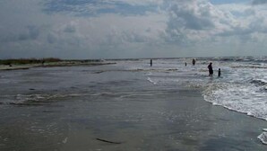 A beach with people walking along the shore and a cloudy sky. - St. Simons Island secret! (St Simons Island)