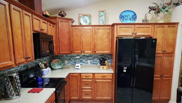 A kitchen with wooden cabinets, a black refrigerator, a microwave, and a blender on the counter. - Custom home great local, boat parking,  near dock, food, scalloping,  Manatee. (Homosassa)