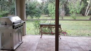 A patio with a grill, a table, and a view of a garden. - Custom home great local, boat parking,  near dock, food, scalloping,  Manatee. (Homosassa)