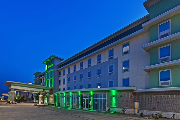 A multi-story hotel with a flat roof and a green-lit entrance. - Holiday Inn Amarillo East by IHG (Amarillo)