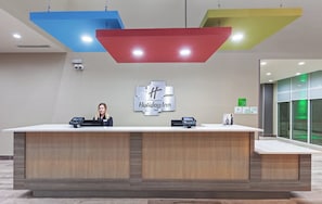 Ein Empfangsschalter mit einem 'Holiday Inn'-Schild, Überwachungskameras und einem digitalen Check-in-Terminal.