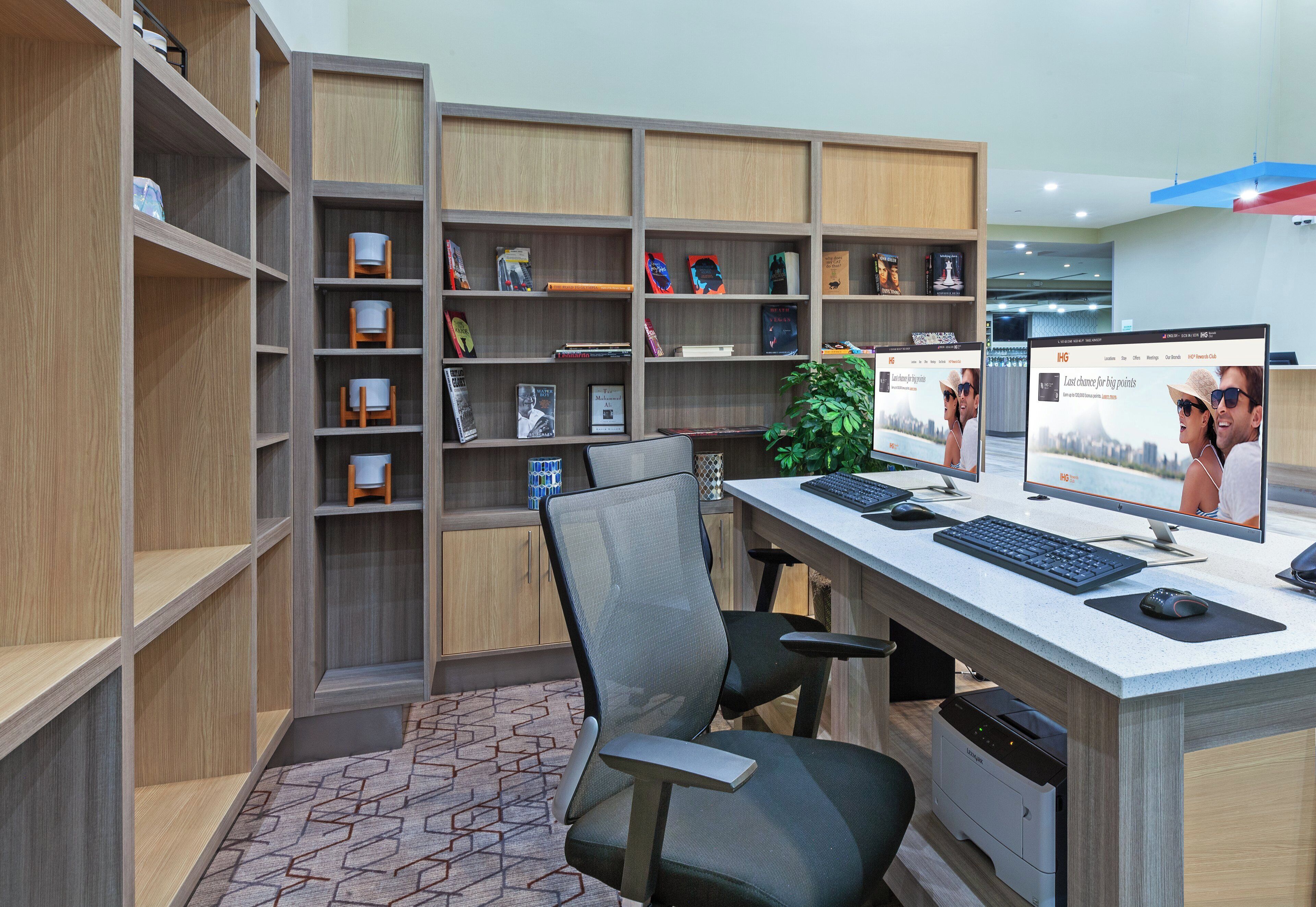 A modern office space with a desk, two chairs, a bookshelf, and a printer.