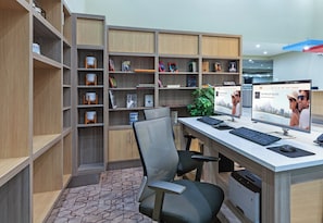 Ein modernes Büro mit Schreibtisch, zwei Stühlen, einem Bücherregal und einem Drucker.