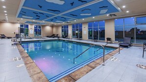 An indoor swimming pool with clear water, surrounded by lounge chairs and a ceiling with a sun and cloud design. - Holiday Inn Amarillo East by IHG (Amarillo)