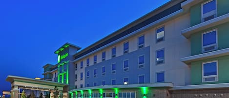 Un hotel de varios pisos con fachada plana, amplias ventanas y un letrero de Holiday Inn.