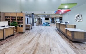 A hotel lobby with wooden reception desks, a seating area, and a large screen on the wall. - Holiday Inn Amarillo East by IHG (Amarillo)