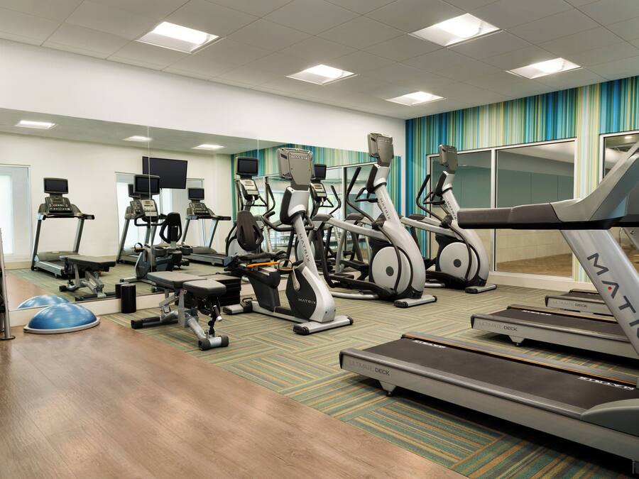 A gym with various exercise equipment including treadmills, stationary bikes, and weight machines.