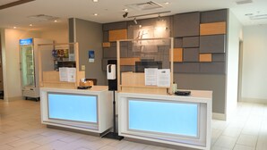 A reception area with two reception desks, a glass partition, and a wall with geometric patterns. - Holiday Inn Express & Suites Middletown by IHG (Middletown)