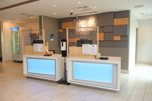 A reception area with two reception desks, a glass partition, and a wall with geometric patterns. - Holiday Inn Express & Suites Middletown by IHG (Middletown)