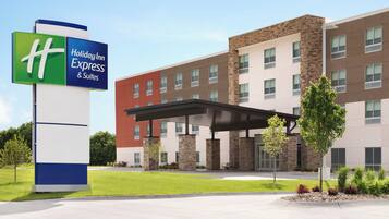 A Holiday Inn Express & Suites hotel with a modern building facade, a covered entrance, and a well-maintained lawn.