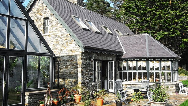 A house with a stone exterior, large windows, and a conservatory with a glass roof. - Luxury House on Seafront, with Pool, Sauna, Jacuzzi and Woodlands (castletownbere)