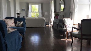 Una habitación espaciosa con una cama grande, un sofá azul, una silla de madera y un aparador.