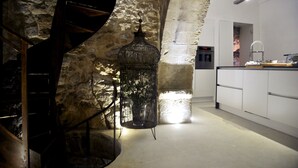 Una cocina moderna con un fondo de pared de piedra, una escalera de caracol y una lámpara colgante.