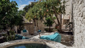 Un patio con piscina, paredes de piedra y mobiliario exterior.