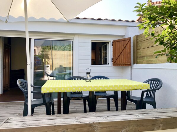 A patio with a table and chairs, a wooden fence, and a sliding glass door. - Best location for your holidays, cozy villa at bottom of the Bourdaines dunes! (Seignosse)