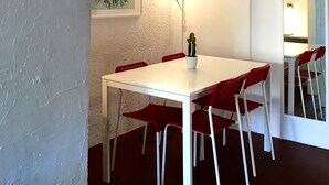 Ein Essbereich mit einem weißen Tisch und roten Stühlen, einer Kakteenpflanze auf dem Tisch und Kunstwerken an den Wänden.