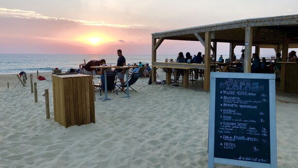Ein Restaurant am Strand mit Außenbestuhlung und einer Speisekarte.