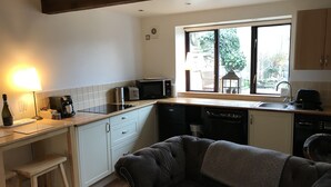 A compact kitchen with a dining area, a window with a view, and a cozy seating area. - Traditional Lakeland Hideaway Cottage for two, close to the Lakes and Dales (KENDAL)