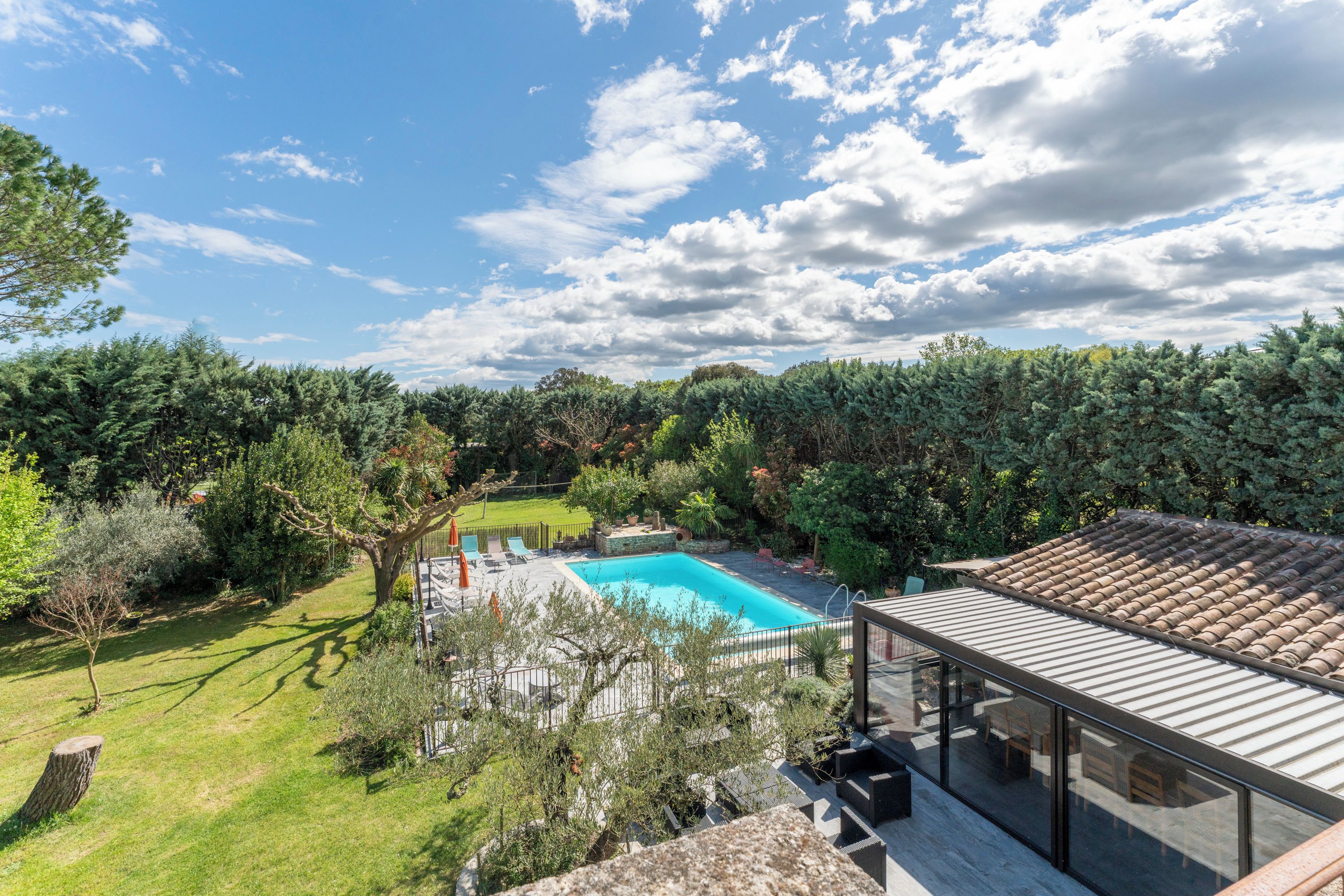 Una propiedad residencial con piscina, abundante vegetación y cielo despejado.