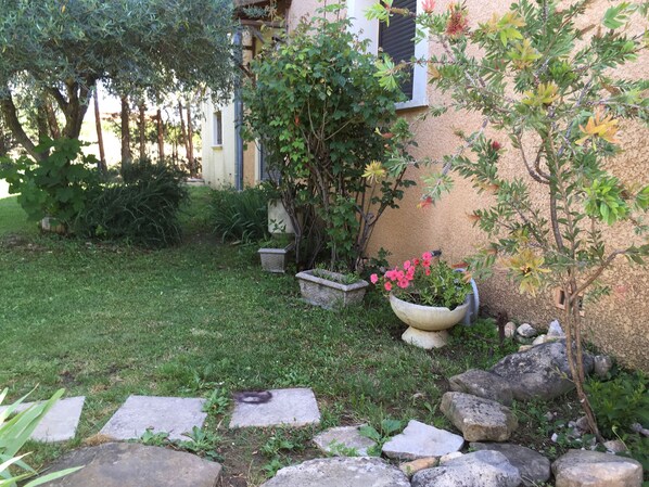 Ein Garten mit einem Kiesweg, Blumentöpfen und einem kleinen Baum.