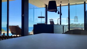 A modern dining area with a large table, chairs, and a view of the ocean through large windows. - VILLA LUXE SA TUNA, heated mirror pool VERY BEAUTIFUL SEA VIEW (Begur)