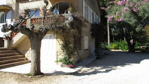 A two-story house with a balcony, a staircase leading to the entrance, and a garden with flowering plants. - BANDOL- Nice apartment - CLIM - 80 m from the SEA- 4 pers- 10 min walk from the center (Bandol)