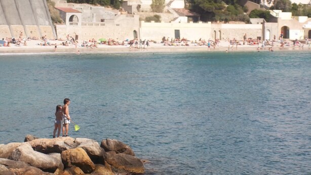 A coastal scene with a rocky outcrop where two people are standing. - BANDOL- Nice apartment - CLIM - 80 m from the SEA- 4 pers- 10 min walk from the center (Bandol)