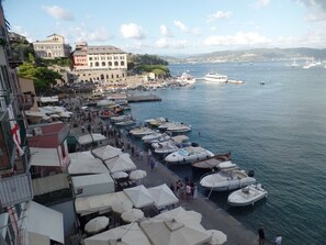A coastal marina with boats docked and people walking along the pier.