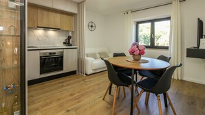 A modern kitchen with wooden cabinets, a built-in oven, and a dining area with a round table and chairs. - Holiday house Roža * large garden, sun terrace, BBQ, free WiFi (Labin)