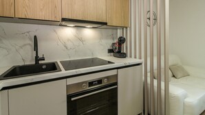 A compact kitchen with a sink, stove, and oven, wooden cabinets, and a white countertop. - Holiday house Roža * large garden, sun terrace, BBQ, free WiFi (Labin)