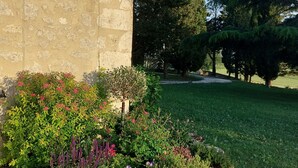 A building with a stone facade and a garden with various plants and flowers. - 18th century Gersoise house, secluded, swimming pool, wooded grounds (La Romieu)