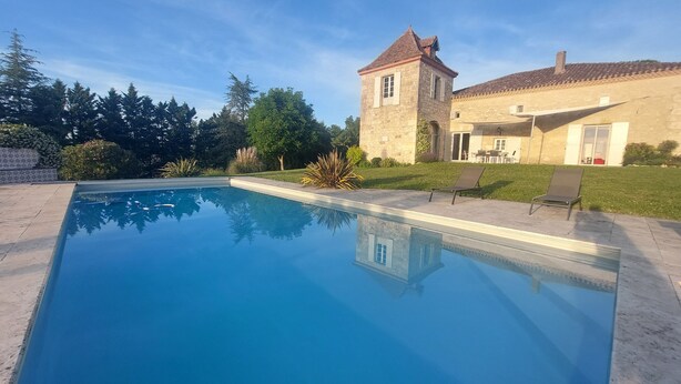 A swimming pool with a stone building in the background. - 18th century Gersoise house, secluded, swimming pool, wooded grounds (La Romieu)