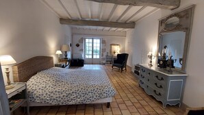 A bedroom with a large bed, a dresser, a chair, and a mirror. - 18th century Gersoise house, secluded, swimming pool, wooded grounds (La Romieu)
