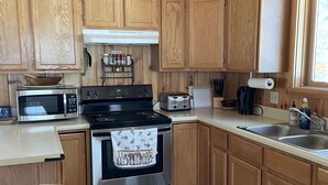 Una cocina con armarios de madera, microondas, estufa, tostadora y un lavabo.