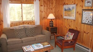 Un salón acogedor con un sofá, un sillón y una mesita baja con libros.